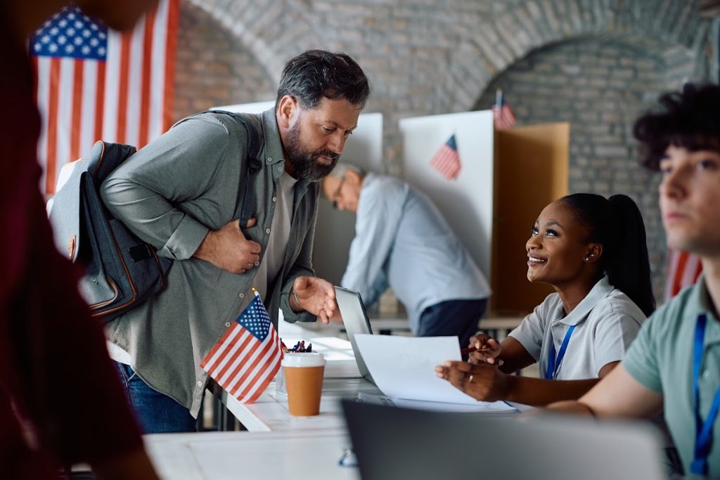 Volunteer engaging with voter at polling station, emphasizing civic involvement in the 2024 elections.