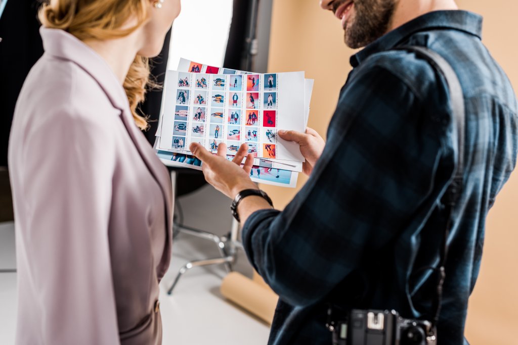 Photographer and model reviewing contact sheets in studio setting.