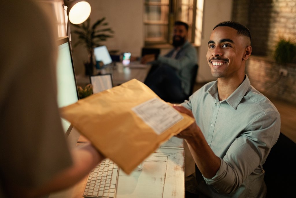 Man receiving package at office desk smiling