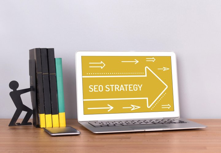 Figurine pushing books near laptop with SEO strategy