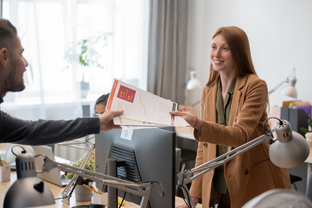 woman handing business report to colleague