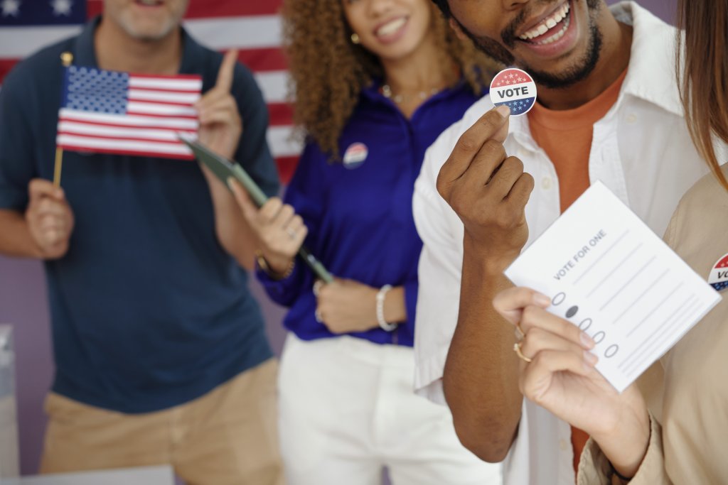 Man holding vote sticker and ballot smiling