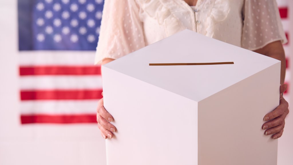 Woman holding ballot box with US flag background
