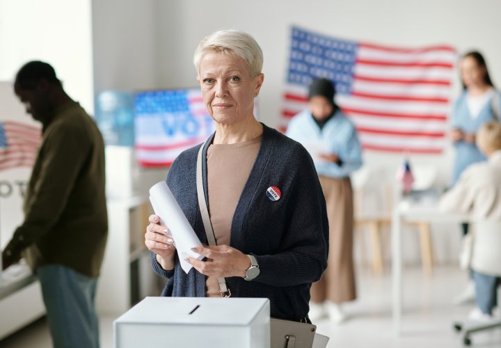 Older woman casting ballot at voting station
