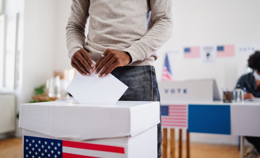 Man casting ballot in American voting booth